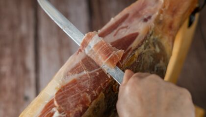 spanish acorn-fed iberian ham close-up open knife cut by the hands of a charcuterie woman