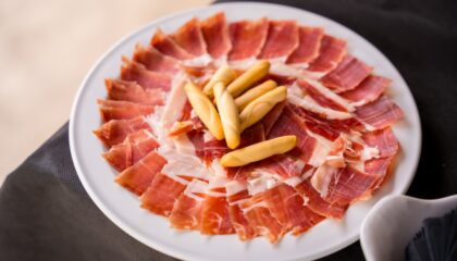 Dish with Iberico ham cut ready to eat. Ham cutter man. Service of a person cutting a piece of ham. traditional food of spain